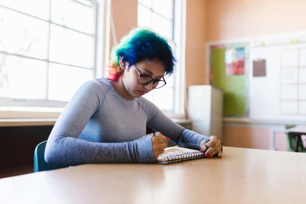 Student studying in a classroom while preparing for UVA SAT requirements with focused note-taking and test practice efforts.