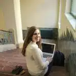 student sitting down in the staircase smiling about the claremont mckenna gpa requirements