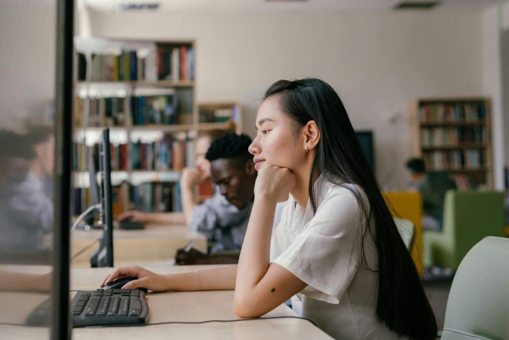 A high school student studies a computer screen while participating in an economics internship.