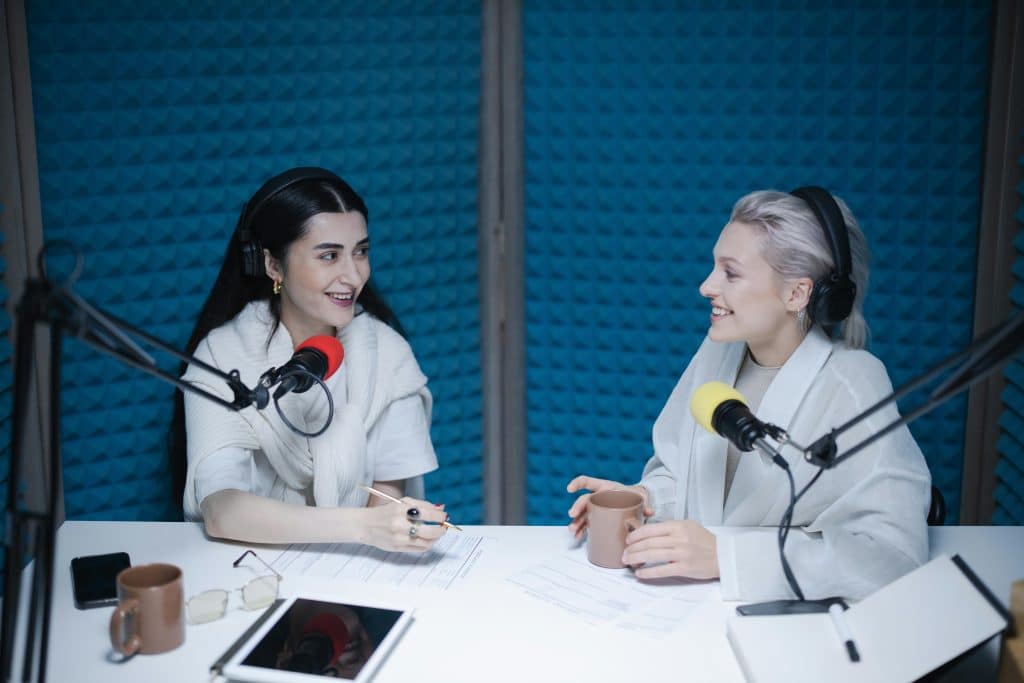 Two young women recording a podcast in a studio with microphones, representing journalism internships for high school students.