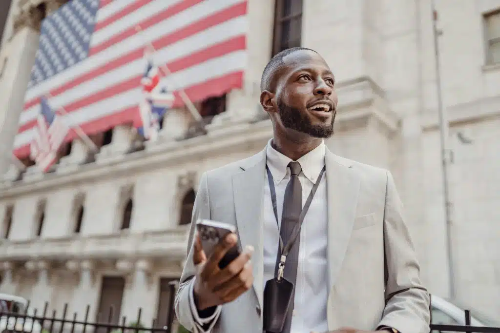 A professionally dressed individual standing outside a government building with an American flag, representing government internships for high school students.