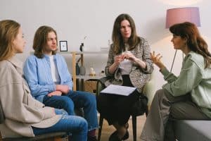 Group of high school students talking with an instructor in a small workshop setting, related to Psychology summer programs for high school students