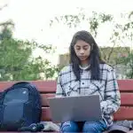 A college-bound female student using her laptop to research Brown vs Harvard.