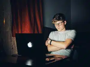 A young man on his laptop searching for business research topics for his high school research project.