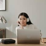 student in white sweater smiling whilst researching for the regular decision release dates of colleges