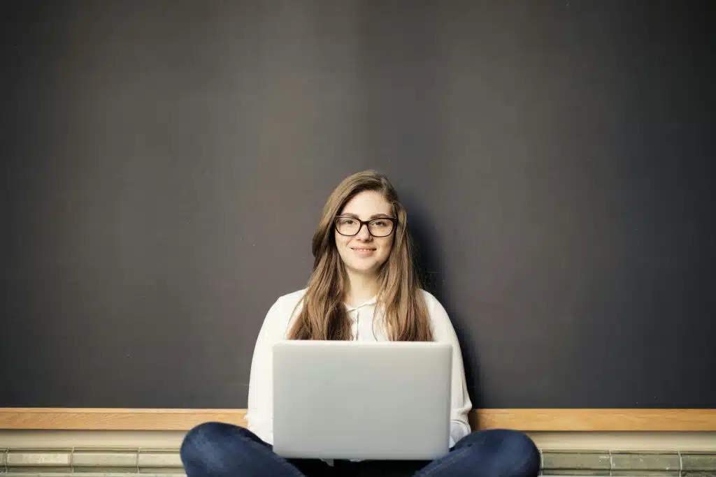 student smiling with a laptop on her lap checking for when UIUC decisions come out