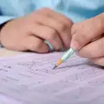 Student filling out a multiple-choice answer sheet with a pencil.