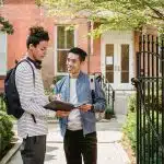 Two college students reviewing notes outside a campus building, representing a UC Berkeley vs MIT comparison in academic environment and student life