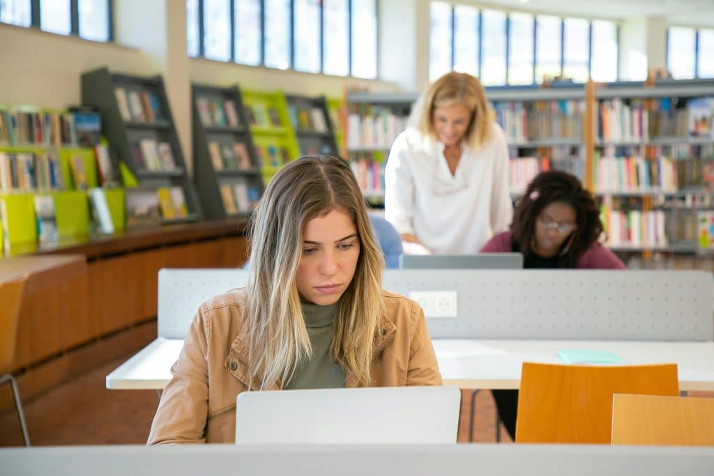 student looking at her computer choosing between uchicago vs harvard school to attend to