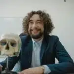 Anthropology student examining a human skull model in a classroom, representing academic study at the best colleges for anthropology