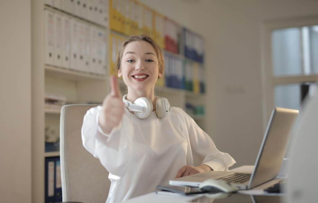 Student smiling and giving a thumbs-up while working on a laptop, illustrating how to be a good student through positive study habits, focus, and active learning.