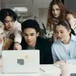 A diverse group of students collaborates around a laptop, reviewing information together during a study session as they research college admissions and the UC Davis acceptance rate.