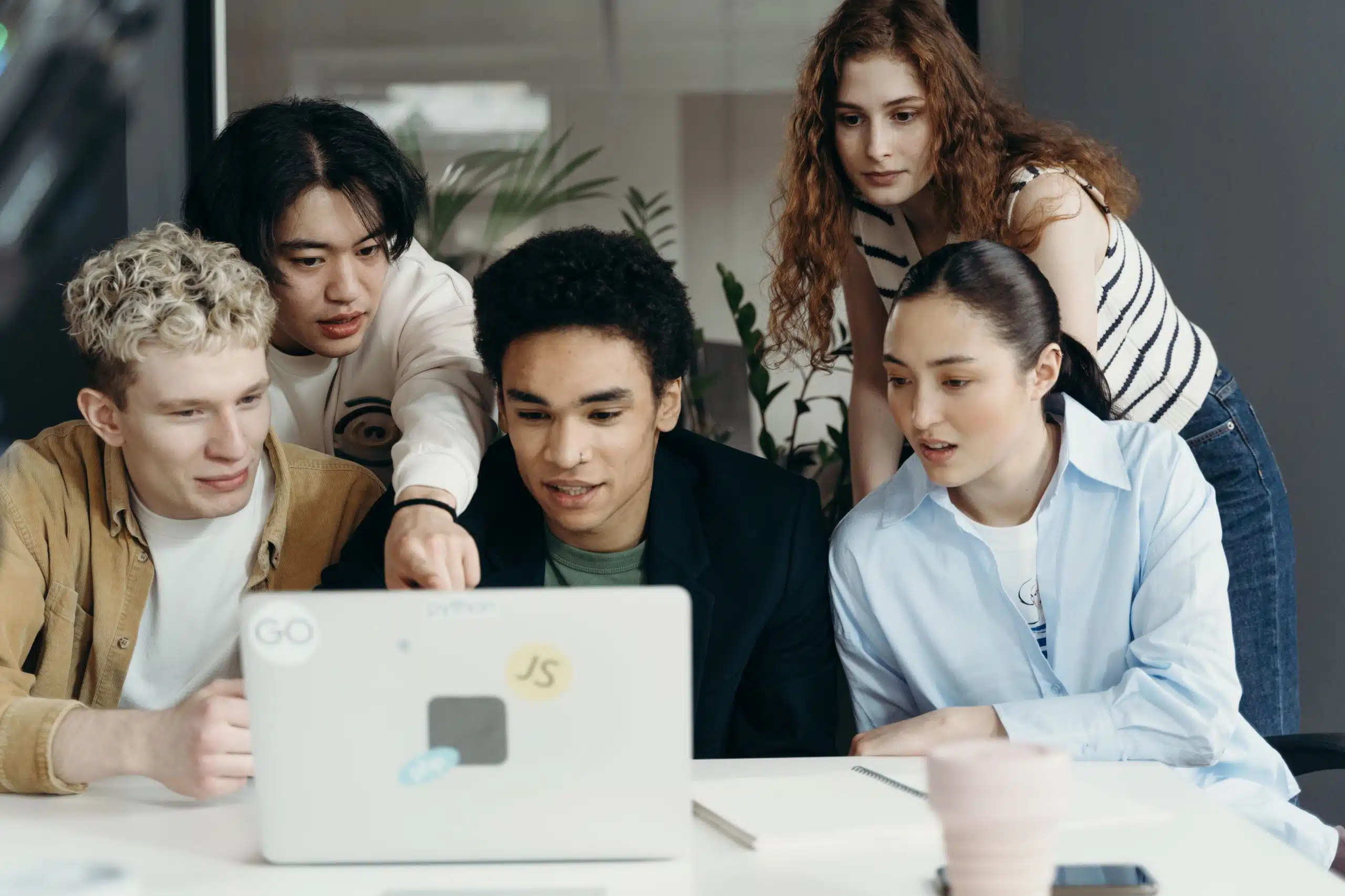 A diverse group of students collaborates around a laptop, reviewing information together during a study session as they research college admissions and the UC Davis acceptance rate.