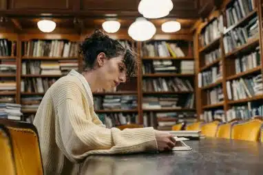 woman in beige studying in a library